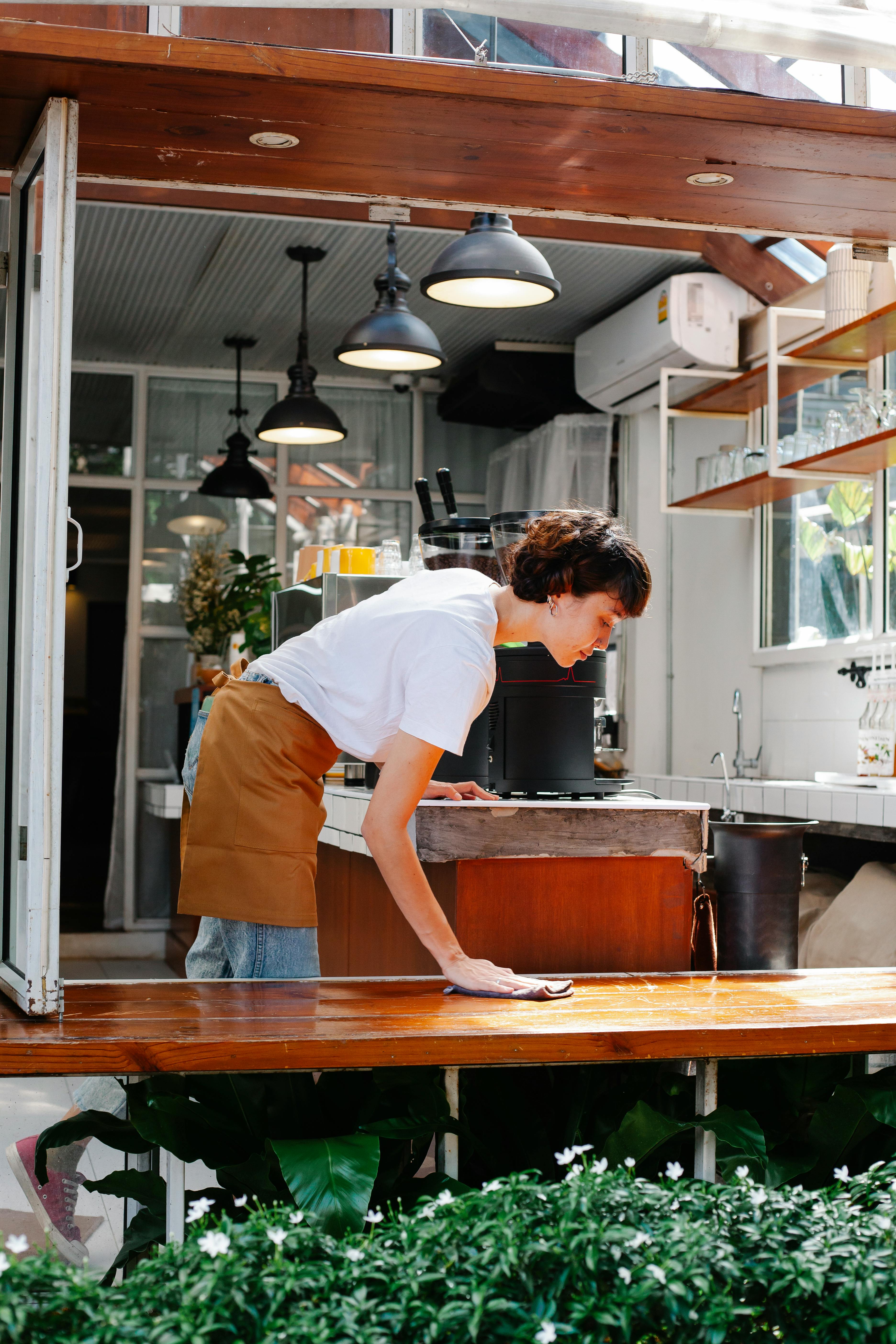 a lady cleaning table with a towel